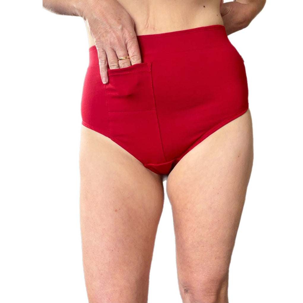 A close-up of a model wearing bright red high-waisted gstring with a front pocket, shown from the waist to the upper thighs against a plain white background.