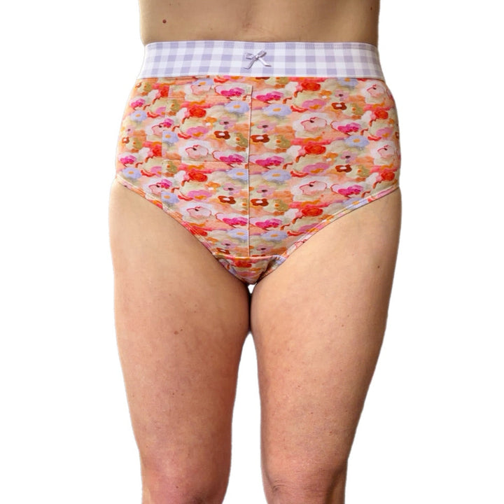 A person wearing high-waisted underwear with a colorful floral print and a white-and-purple gingham waistband, shown against a plain white background.