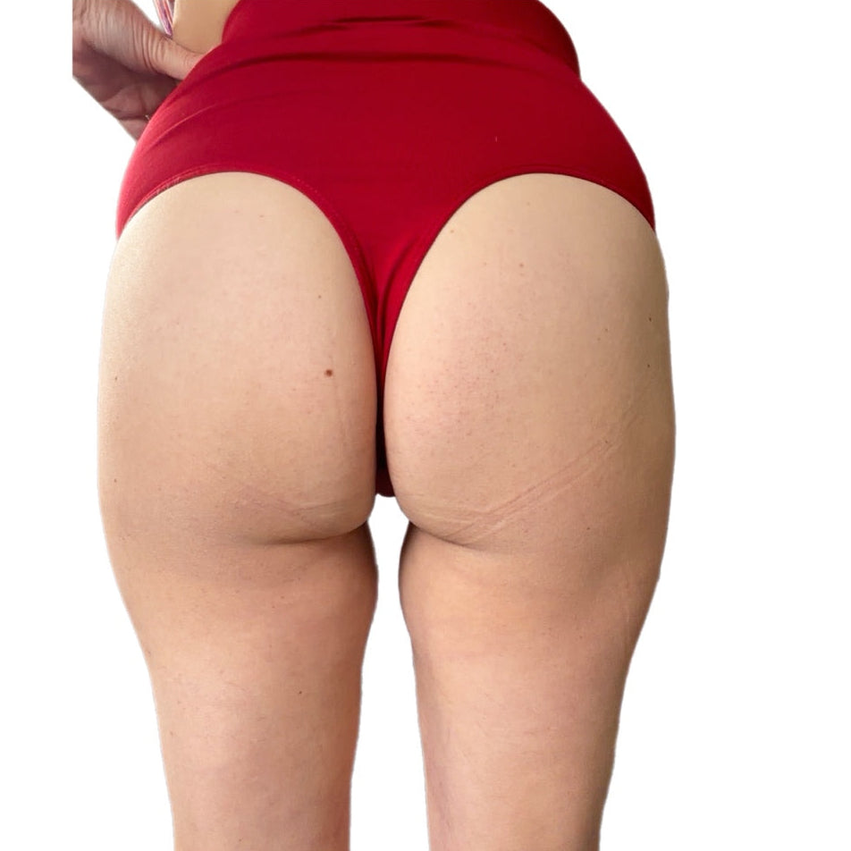 Rear view of a person wearing high-waisted red gstring underwear against a plain white background.