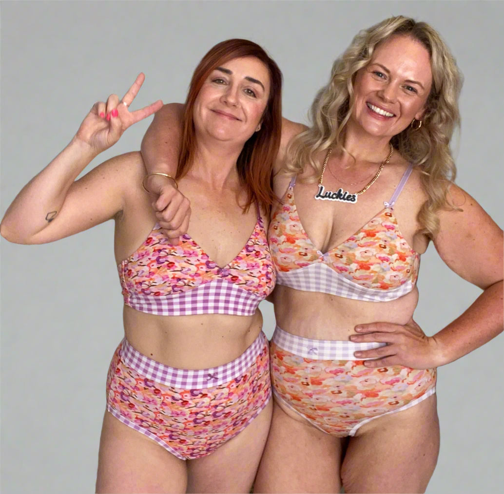 Two women wearing high-waisted discharge underwear and matching bralettes with a floral and gingham pattern. 