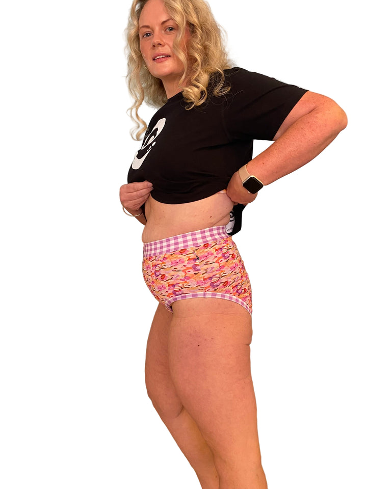 A woman wearing high-waisted discharge underwear with a floral and gingham pattern.