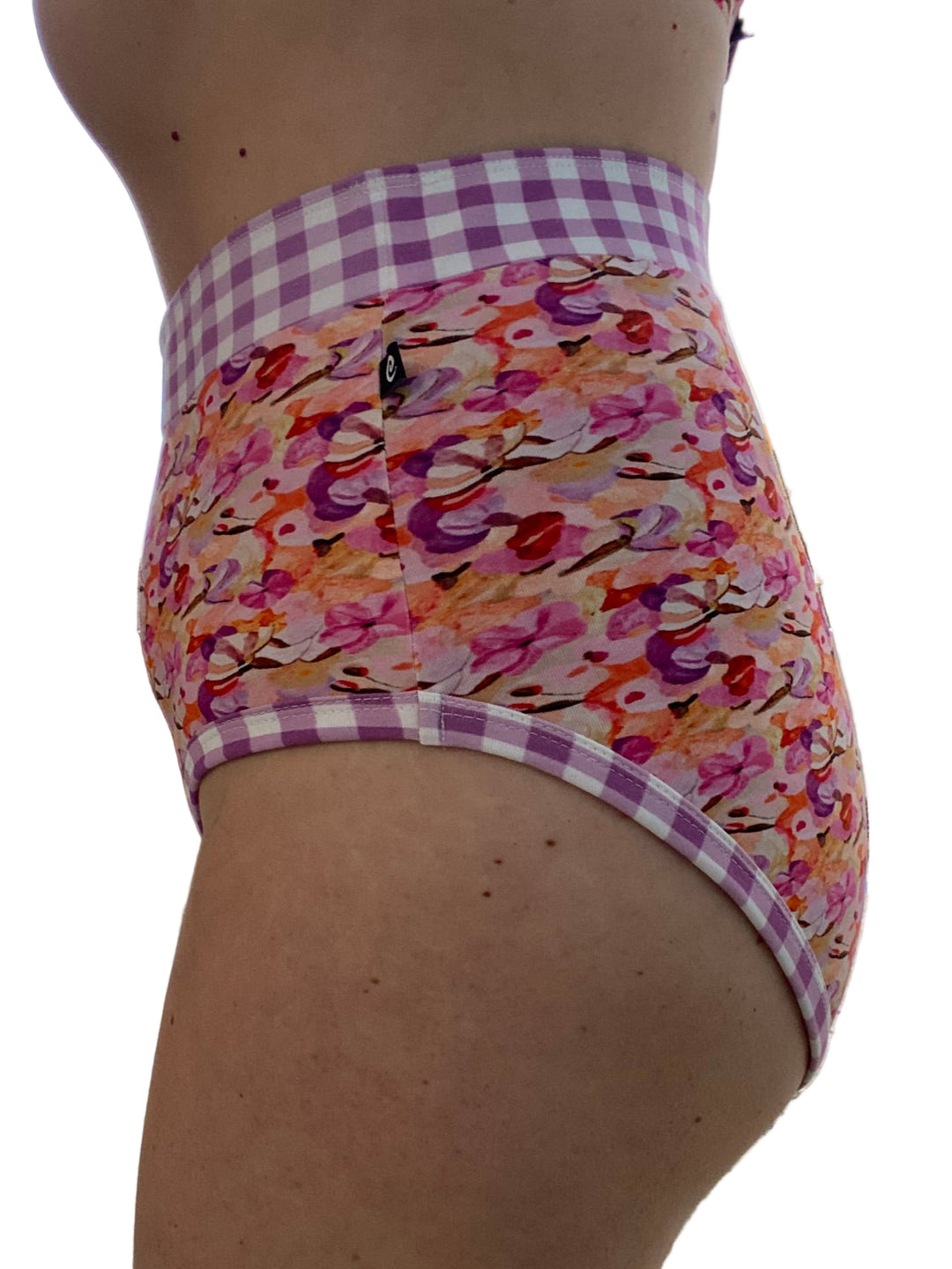 A woman wearing high-waisted discharge underwear with a floral and gingham pattern.