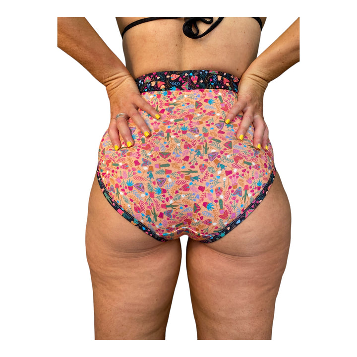 A woman wearing high-waisted discharge underwear with a coral and black pattern.